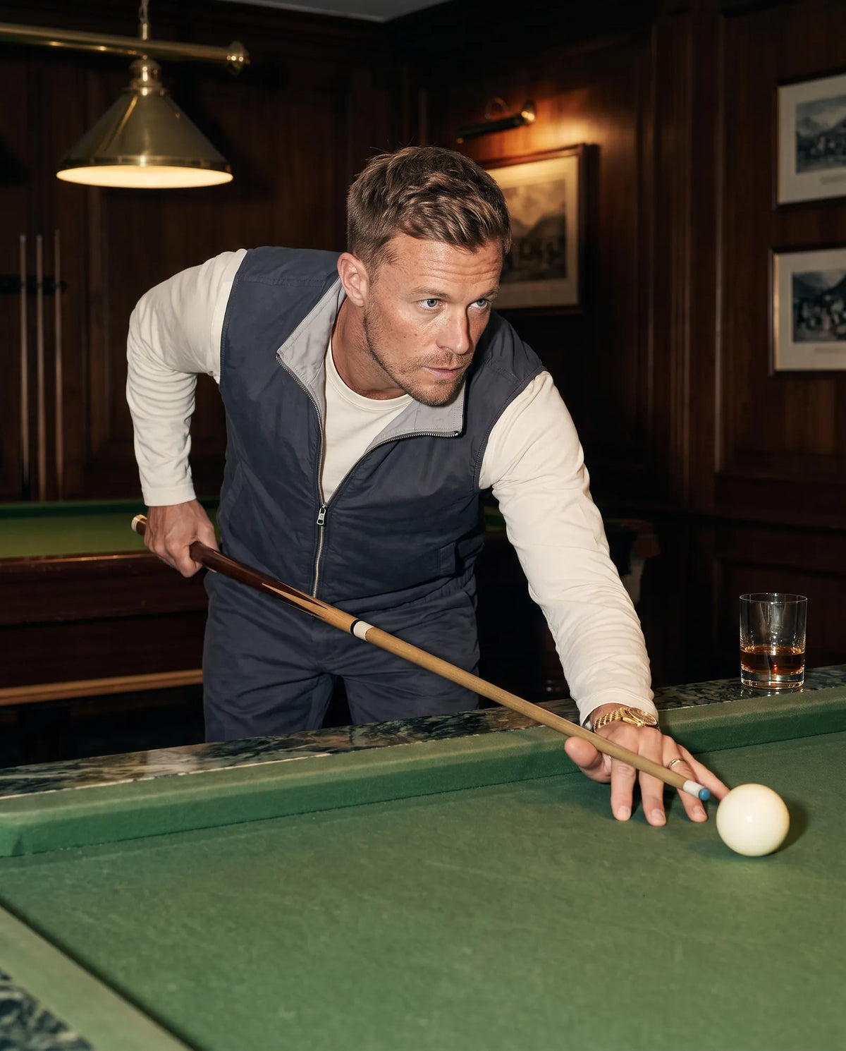 Man lining up a shot in a hotel billiards room in the charcoal Reverso set