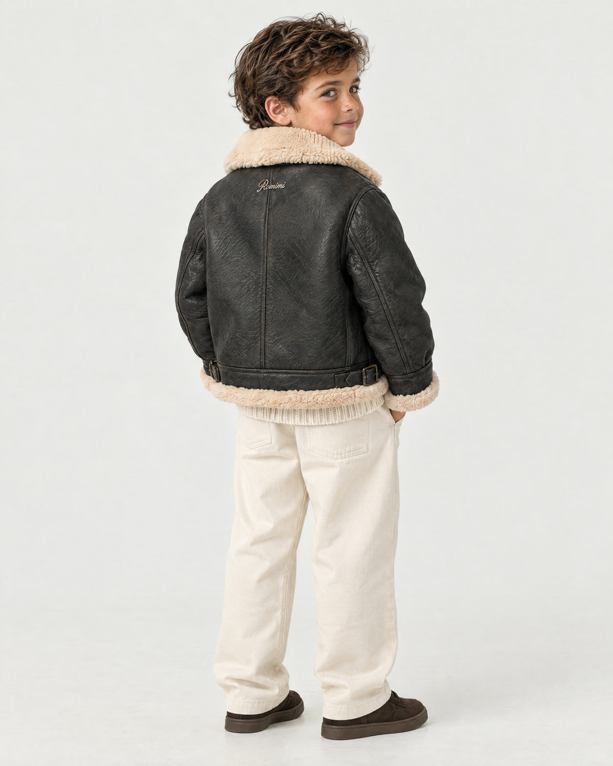 Boy wearing the Romimi kids aviator jacket in black with a cream collar, back view