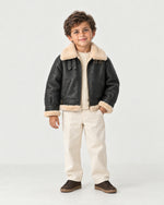 Boy wearing the Romimi kids aviator jacket in black with a cream collar, full length