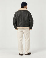Man wearing the Romimi aviator jacket in black with a cream collar, back view