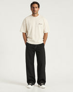 Man wearing the Romimi Graphic Tee - Beige, full length