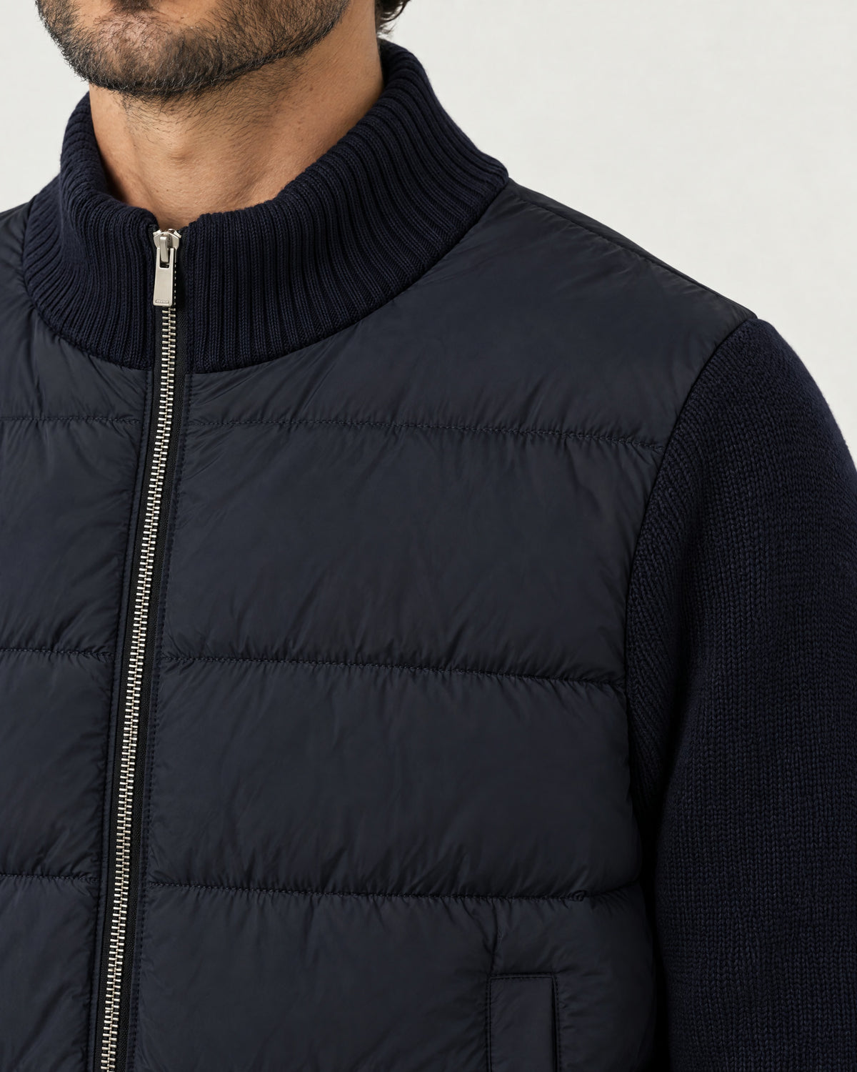 Detail of the Romimi padded knit cardigan in navy: the ribbed knit collar, silver zip and quilted front
