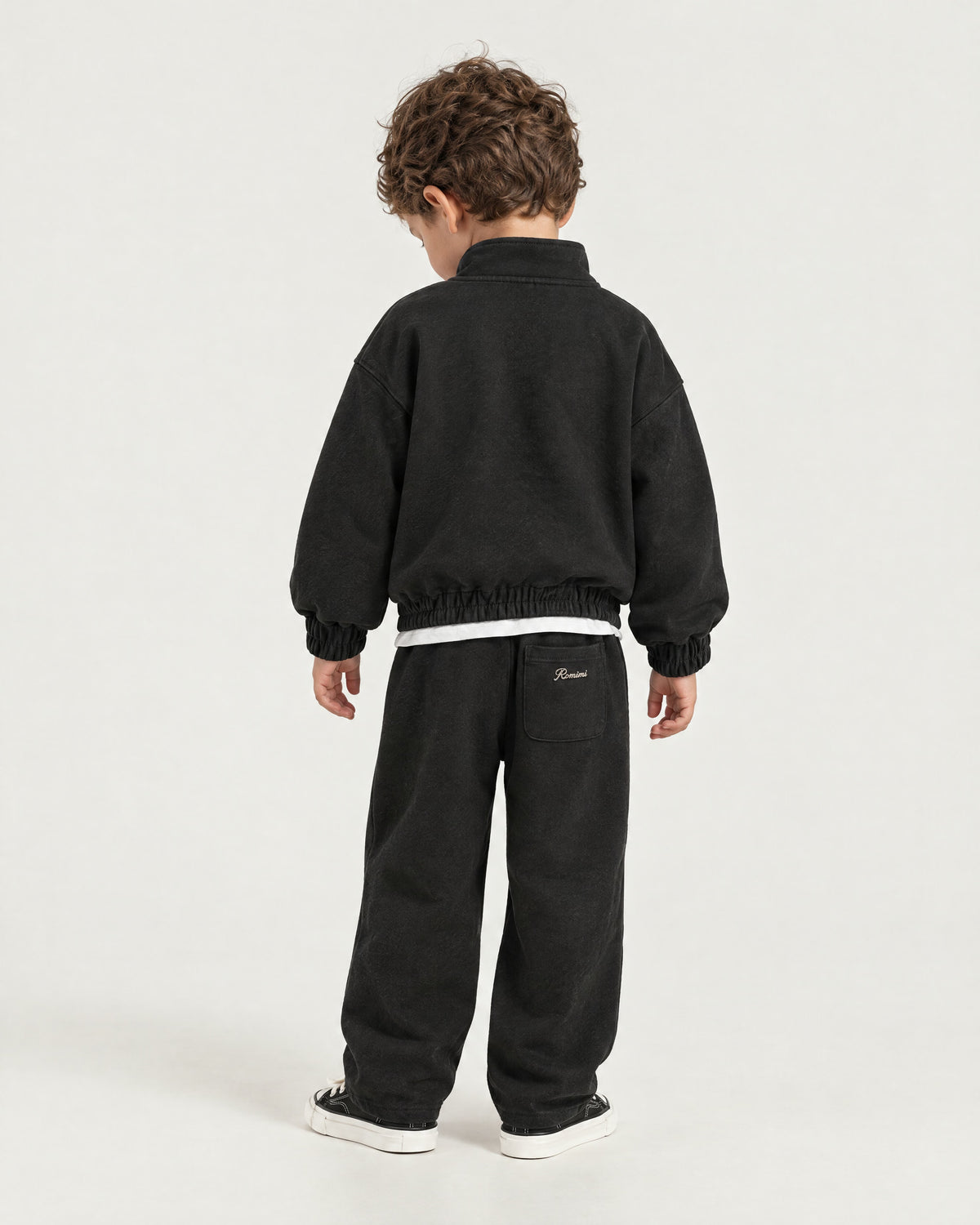 Little boy wearing the Romimi Tracksuit Pant - Black, back view