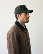 Man wearing the wool baseball cap in dark olive, side view